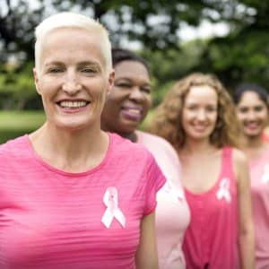 a couple of women standing next to each other wearing a breast cancer ribbon in their shirts.