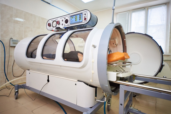 A girl in a black T-shirt lies in a hyperbaric chamber, oxygen therapy.