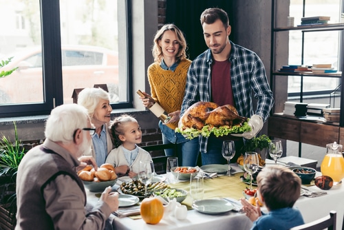 man with delicious turkey for holiday dinner with beautiful family