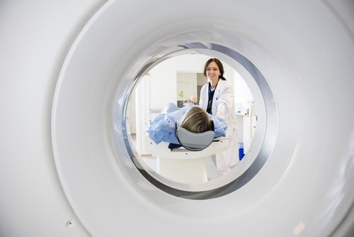 Doctor Looking At Patient Undergoing CT Scan