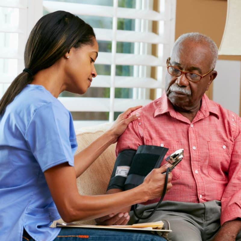 Nurse Visiting Senior Male Patient At Home Taking Blood Pressure