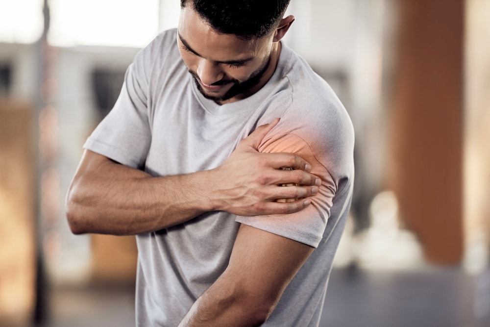 Man holding his shoulder in pain before shoulder replacement surgery.